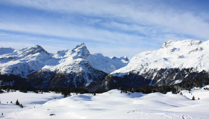 Alp Flix mit schneebedeckten Bergen und Wiesen