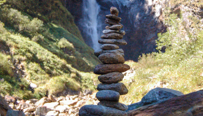 Steinmännchen im Bergtal vor Wasserfall im Sommer