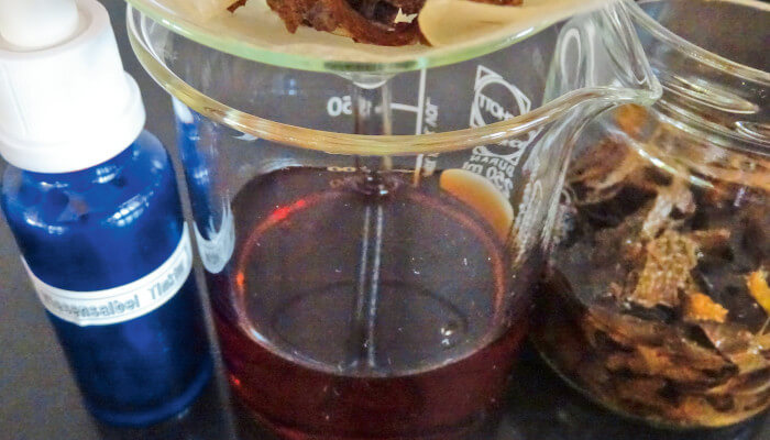 Glasgefäss mit Salbeitinktur und blauer Flasche