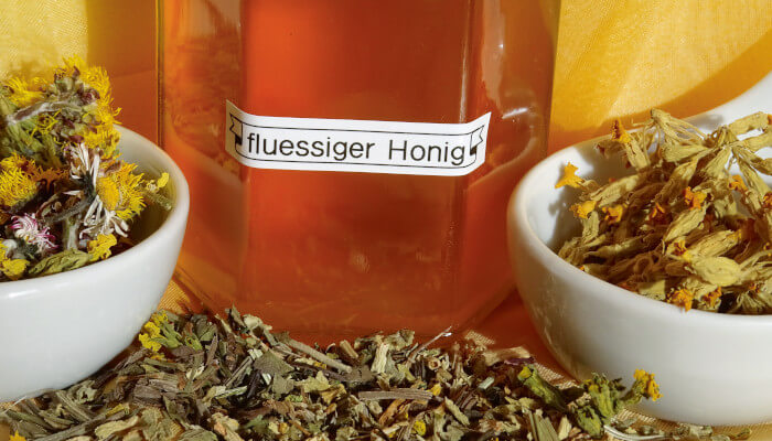 Einmachglas mit Honig und weisse Schüssel mit Schlüsselblumen-Blüten