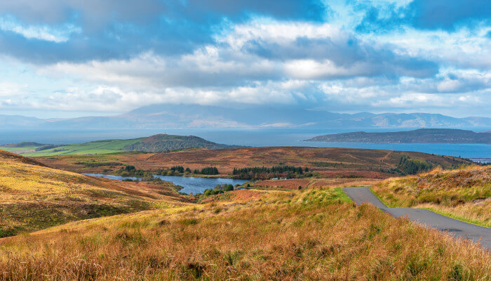 Wiesen und Felder auf einer Insel durch die eine Strasse führt.