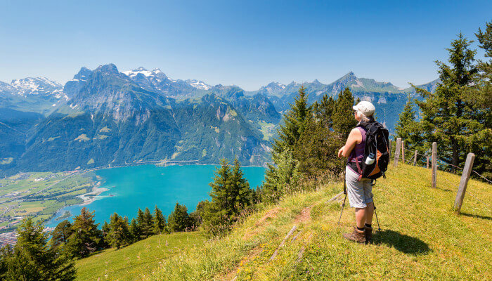 Frau auf einem Wanderweg sieht hinunter zum See