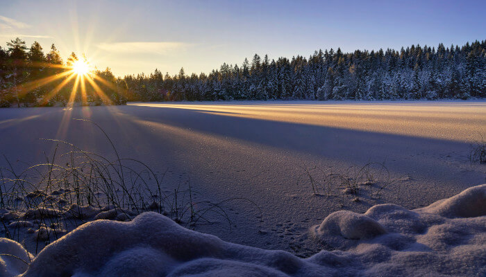 Schneebedeckter und vereister See mit Sonnenuntergang