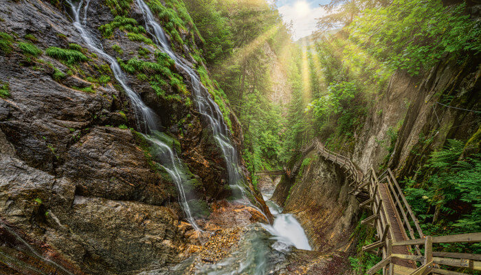 Wasserfälle welche seitlich von den Felsen fliessen mit Gehweg aus Holz