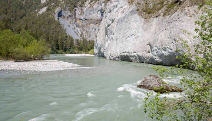 graublauer Fluss fliesst zwischen Bäumen und Felsen